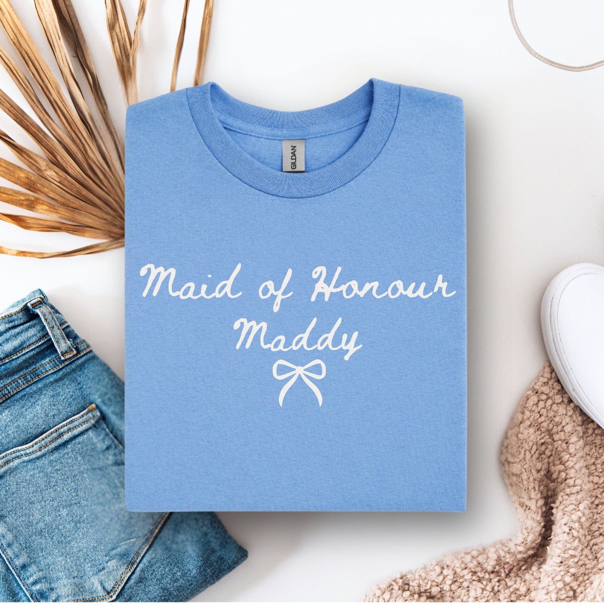 Custom Maid of Honour Shirt light blue folded tee with white script Maid of Honour Maddy and bow flatlay